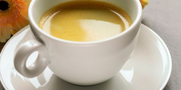Close-up of a creamy espresso in a white cup on a matching saucer.