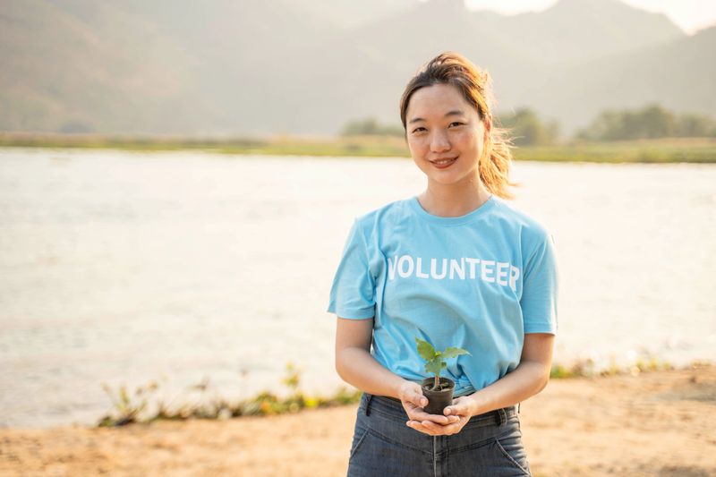Female Volunteer carrying a seedlings to be planted into the soil in the river as save world concept, nature, environment and ecology.