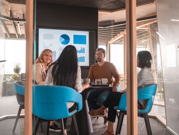 Four colleagues in a meeting room with presentation on screen.