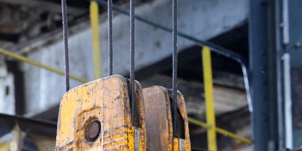 Close-up of a worn yellow pulley block in an industrial setting.
