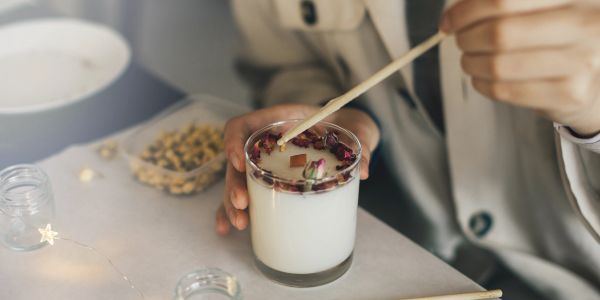 Person stirring a creamy drink with a wooden stick.