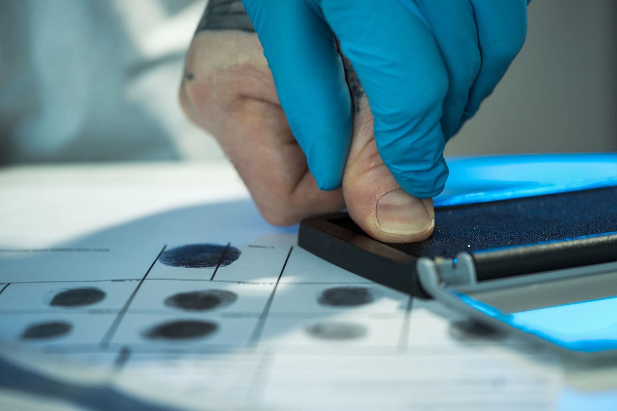 Professional technician performing traditional ink fingerprinting on a physical fingerprint card.