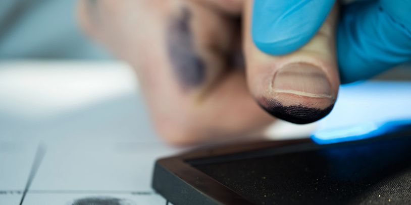Finger with ink being pressed on an ink pad for fingerprinting.