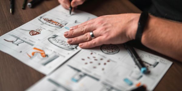 Person drawing sketches on paper with pencils.
