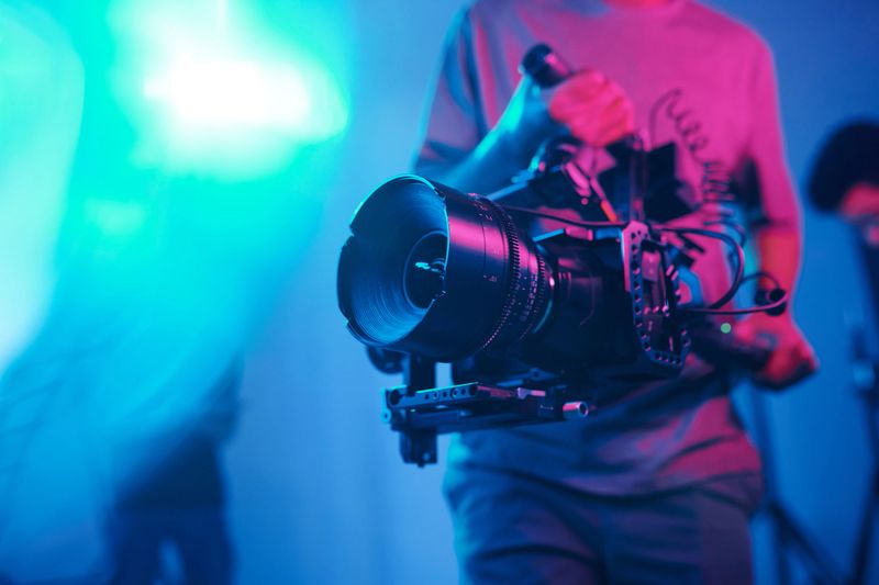 Close-up of young cameraman shooting with professional camera while making content in studio