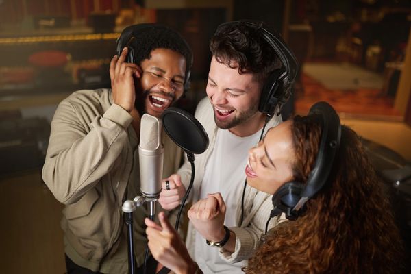Three friends singing together in a recording studio.