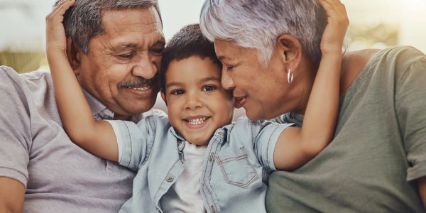 Grandparents hugging their happy grandchild.