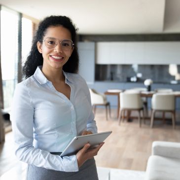 Smiling woman holding a tablet in a bright office.