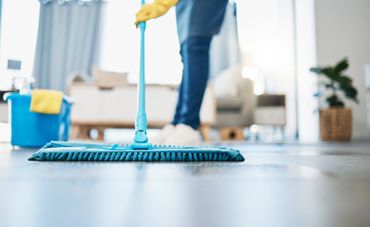 Person mopping floor in a bright, clean living room.