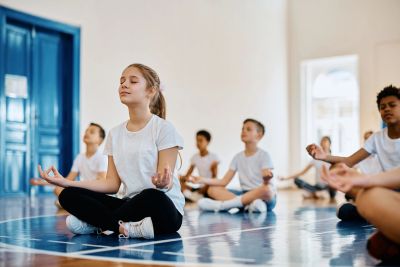 Kids meditating in a gymnasium.