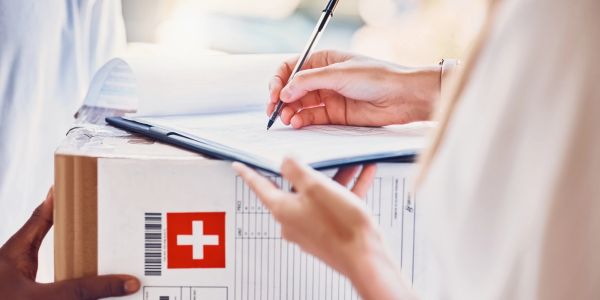 Person signing for a package with Swiss label.