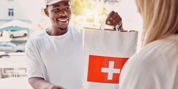 Smiling delivery man handing over a package while customer pays with a card.