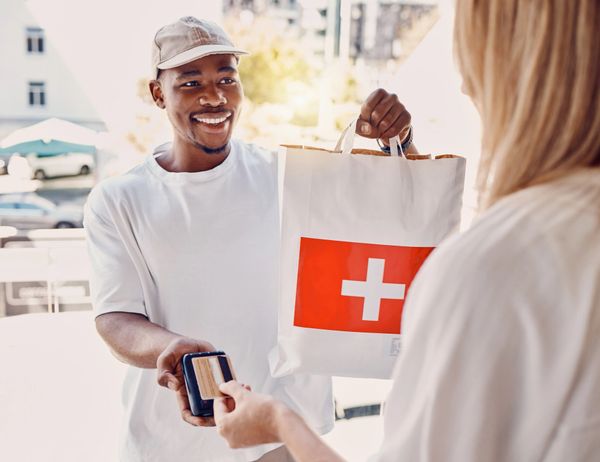 Delivery man hands over a package while customer pays with a card.