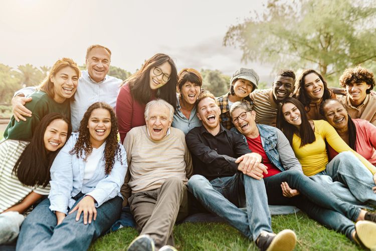 Happy diverse group of people sitting together outdoors, smiling and laughing.