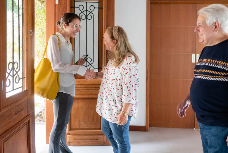 Smiling senior couple shaking hands with a female nutritionist arriving at their home for a diet consultation