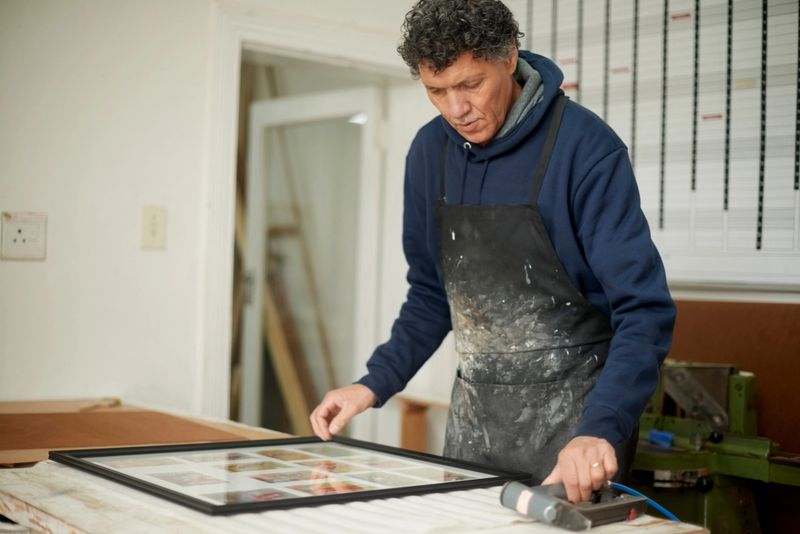 Picture frame, carpenter and mature man worker busy with home construction and project. Renovation workshop, architecture employee and handyman working on wood frames planning for house repairs