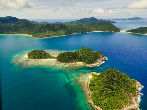 Aerial view of lush islands surrounded by clear blue water.