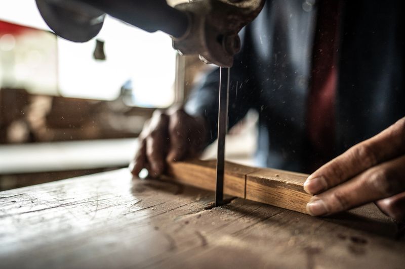 Close-up of a carpenter using sander to cutting piece of wood