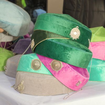 Colorful velvet hats adorned with metallic chains and medallions.