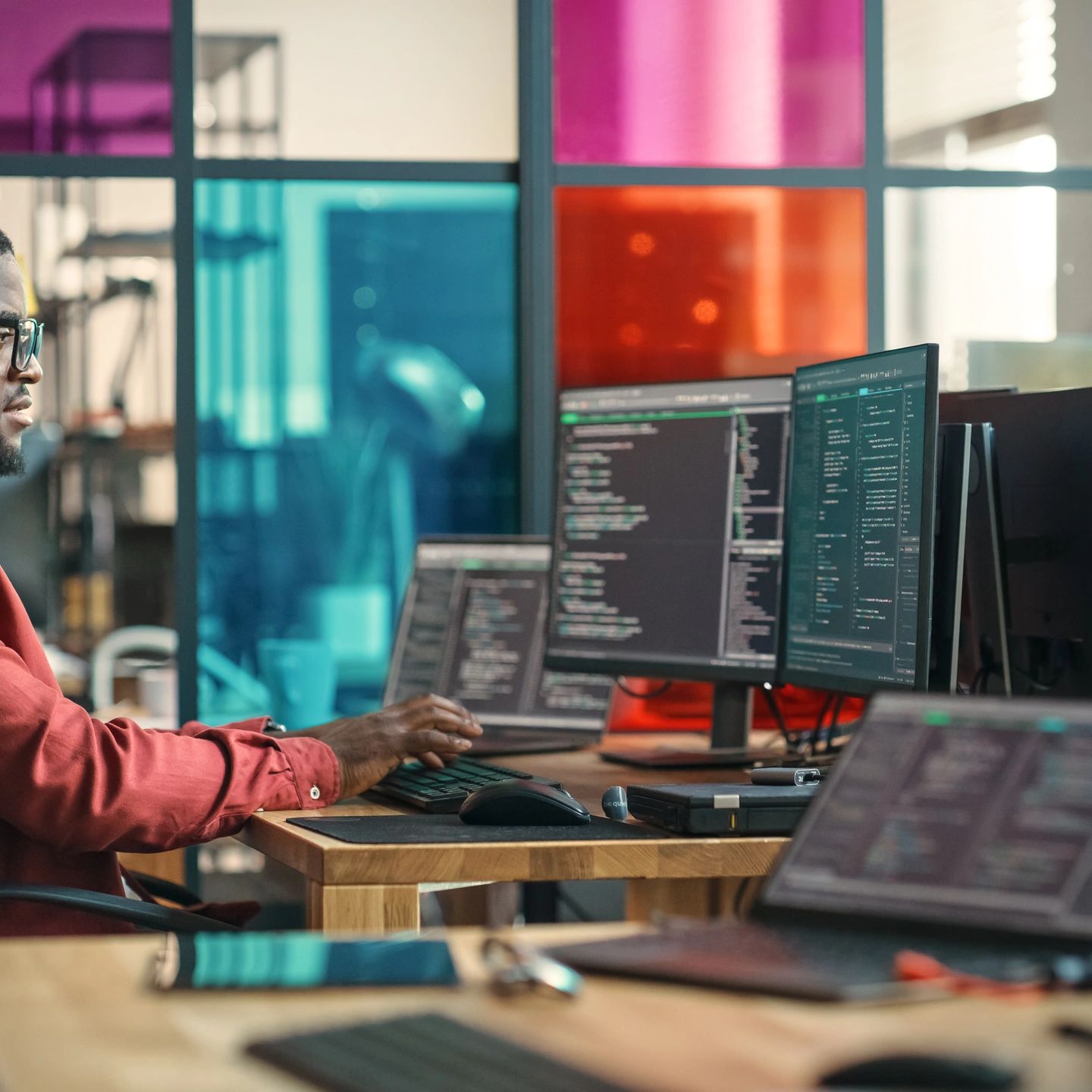 Man programming on multiple screens in a colorful office space.