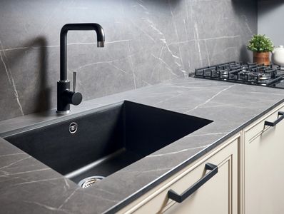 Modern kitchen countertop with black sink and faucet, and gas stove.