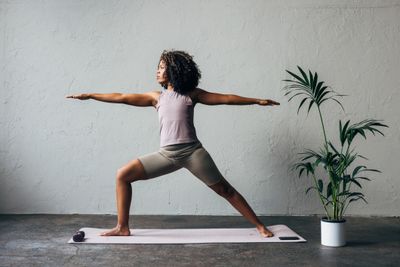 Woman practicing yoga in warrior pose on a mat indoors.