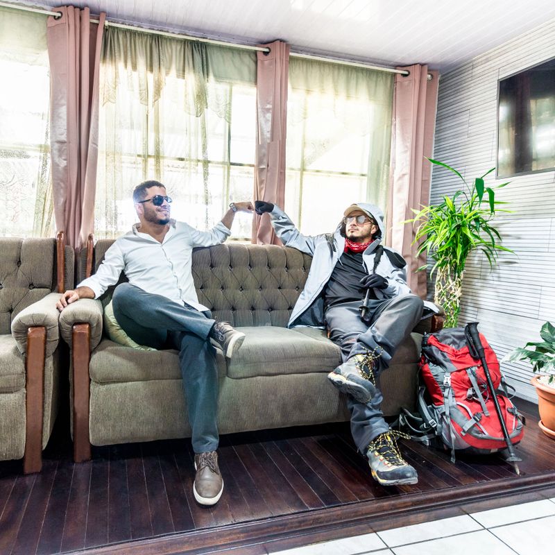 an office worker making peace with his mountaineering adventurer alter ego on a sofa in the living room of the house