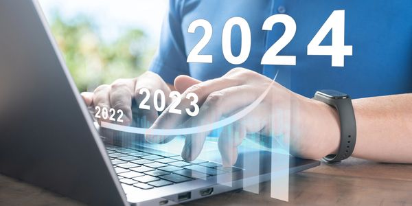 Person typing on laptop with growing year numbers 2022 to 2024 and upward graph.