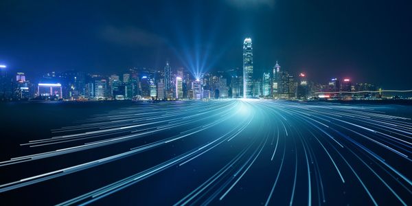 City skyline at night with futuristic light trails converging towards buildings.