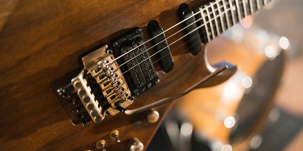 Close-up of a wooden electric guitar with strings and pickups.