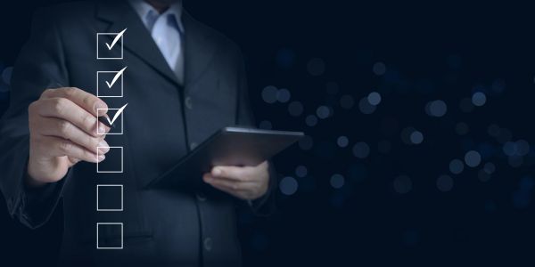Businessman marking checkboxes on a transparent digital list with a tablet.