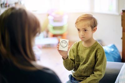 Child showing a card with an angry face to adult.