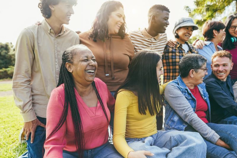 Group of multigenerational people smiling in front of camera - Multiracial friends with different ages having fun together - Main focus on caucasian senior face