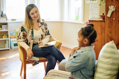 Therapist talking to a child in a cozy room.
