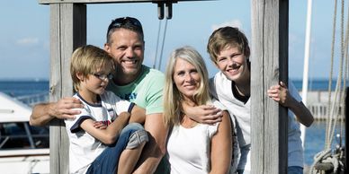 Family posing together on a wooden frame near the water.