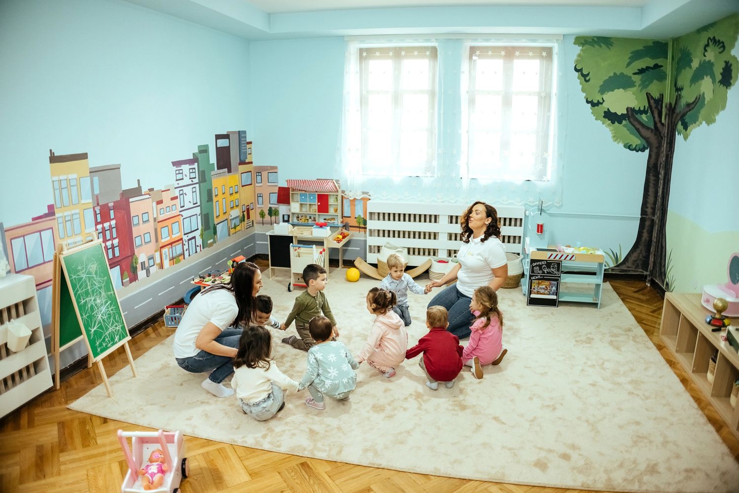Teacher joyfully interacting with children in a colorful classroom.