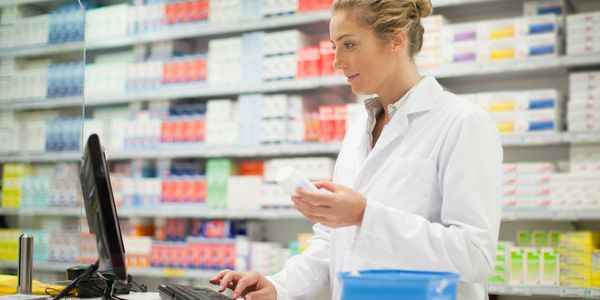 Pharmacist checking medication details at pharmacy counter.