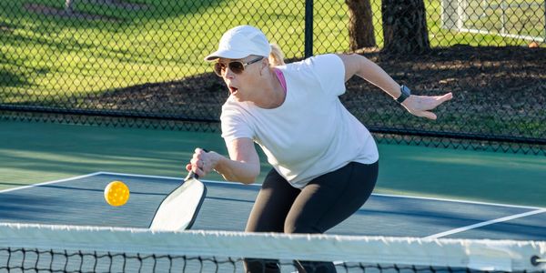 A competitive pickleball match on a sunny day outdoors.

