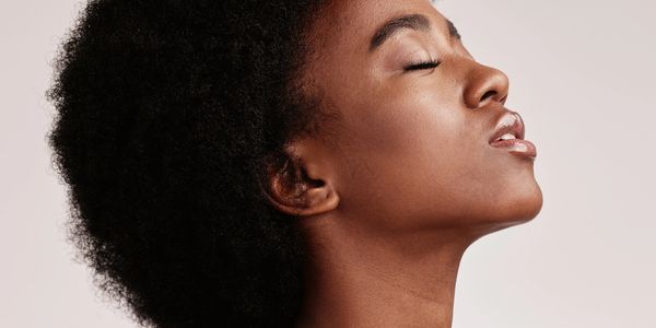 Profile of a woman with natural afro hair and closed eyes, exuding calmness.