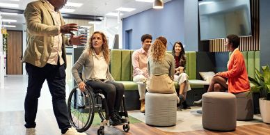 Diverse group discussing in modern office with woman in wheelchair.