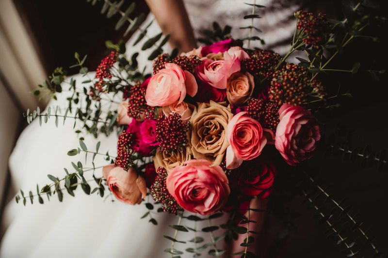Bride in her wedding dress holding bouquet of flowers on her lap