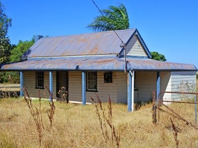 Old, rustic house with a tin roof in dry grassland.