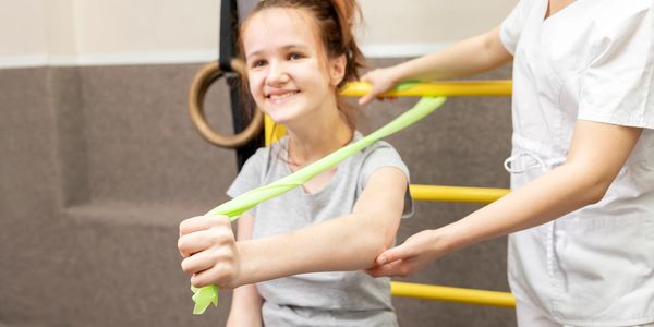 Girl doing arm exercise with a therapist's help.