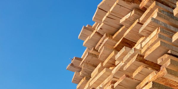Stacked wooden planks against a clear blue sky.