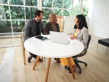 Three colleagues having a meeting around a white table.