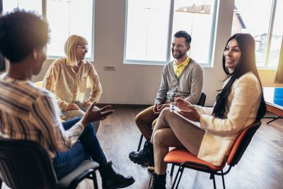 A group of four people sitting and having a friendly discussion indoors.