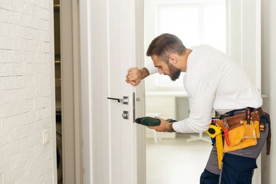 Man installing a door lock with a screwdriver.