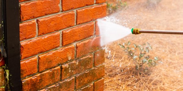 Pressure washing a brick wall.