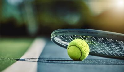 Tennis ball near racket on court line.