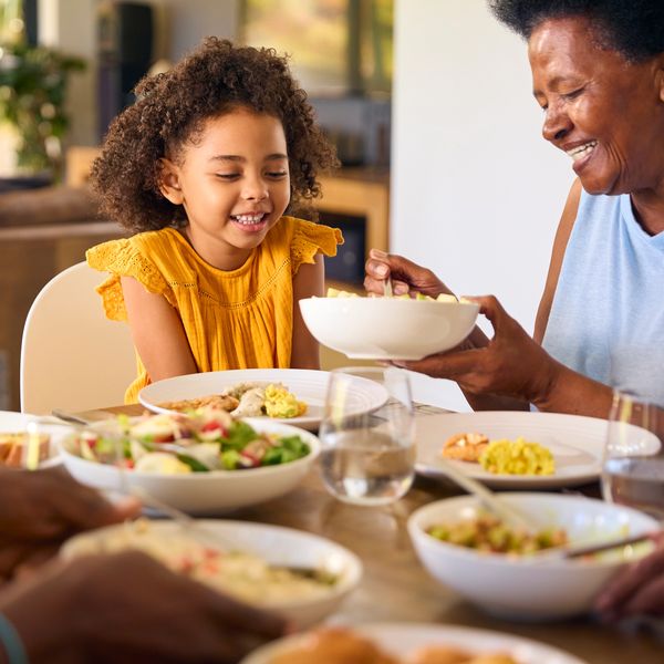 A child and an elder sharing a joyful meal at the dining table.